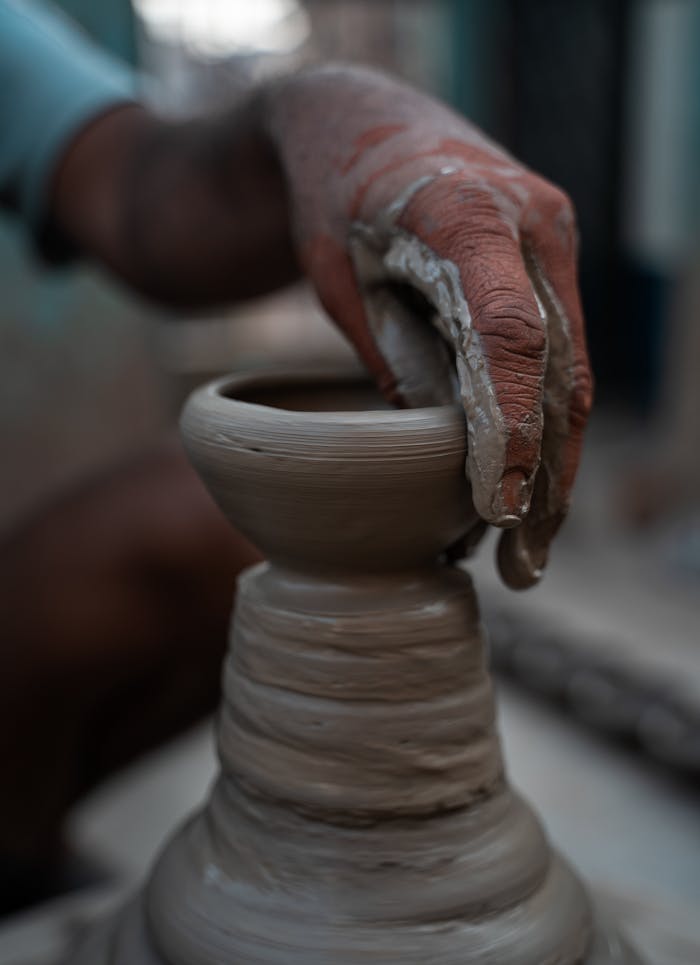 Home A skilled artisan shapes a clay pot on a potter's wheel, highlighting traditional craftsmanship.